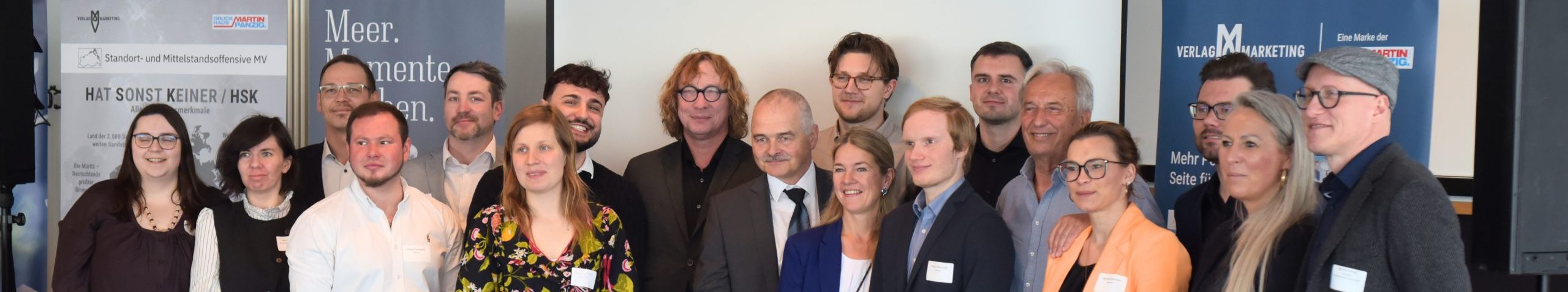 Gruppenfoto der Standortoffensive MV mit Bannern von Meer. Momente erleben. und Verlag MV Marketing